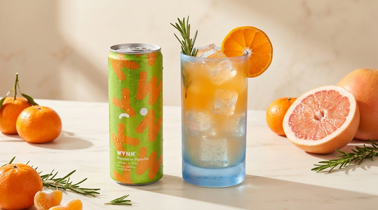 WYNK Mandarin Pomelo THC seltzer beside a mandarin orange mocktail